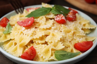 Photo of Tasty pasta with tomato, cheese and basil on table, closeup