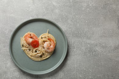 Photo of Heart made of tasty spaghetti, tomato, shrimps and cheese on light grey table, top view. Space for text