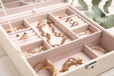 Photo of Jewelry box with stylish golden bijouterie on white wooden table, closeup