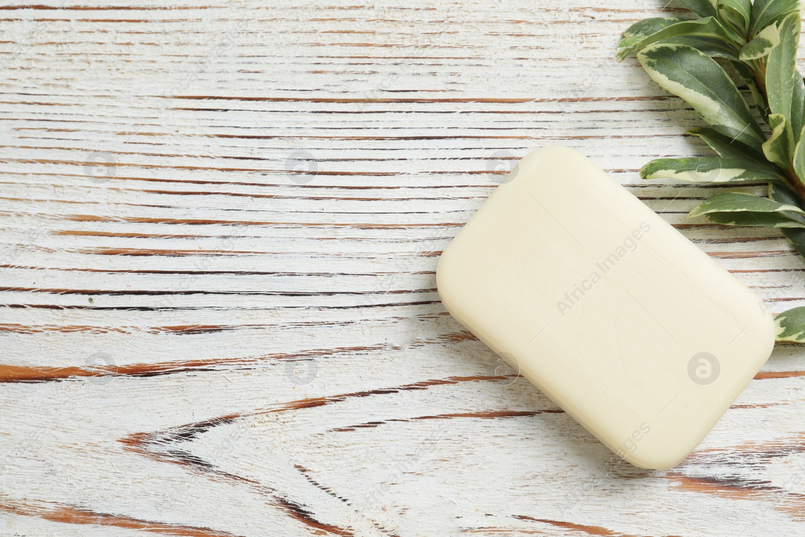 Photo of Soap bar and green plant on wooden table, top view. Space for text