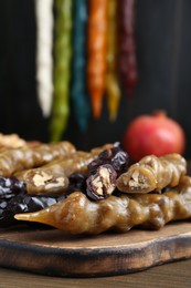 Photo of Many delicious sweet churchkhelas on wooden table, closeup