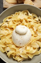 Photo of Delicious pasta with burrata cheese in bowl on table, flat lay