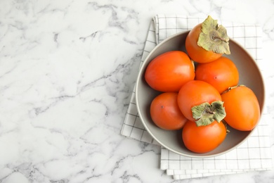 Photo of Tasty ripe persimmons on white marble table, flat lay. Space for text