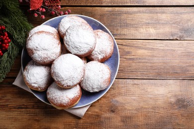 Photo of Delicious sweet buns, fir tree branches and red berries on wooden table, top view. Space for text