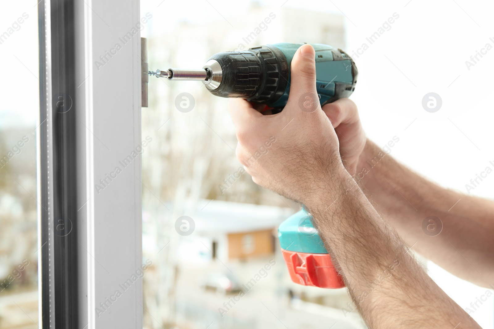 Photo of Construction worker using drill while installing window indoors, closeup