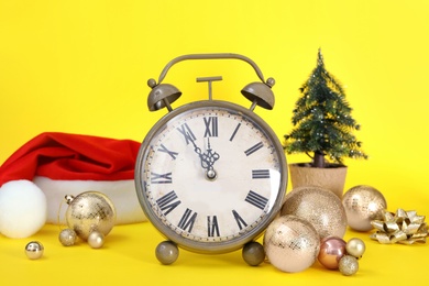 Photo of Vintage alarm clock with Christmas decor on yellow background. New Year countdown