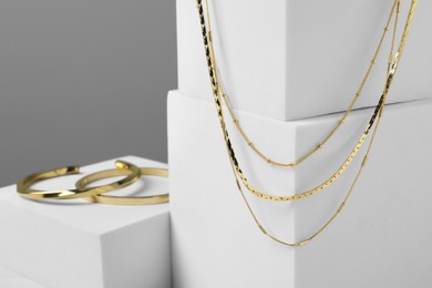 Photo of Stylish presentation of bracelets and necklace on podiums, closeup