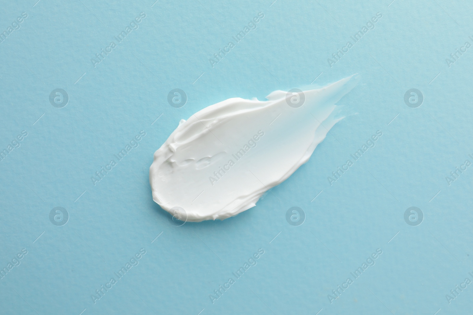 Photo of Sample facial cream on turquoise background, top view