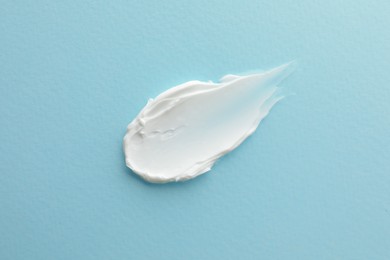 Photo of Sample facial cream on turquoise background, top view