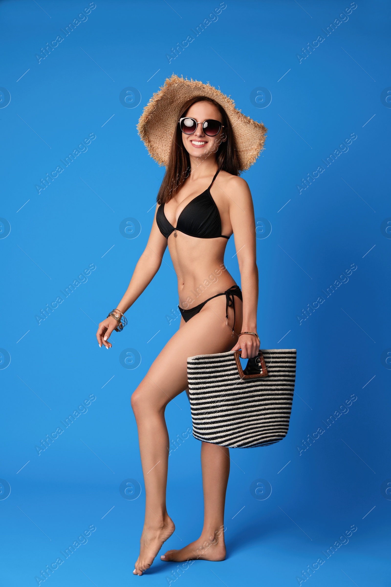 Photo of Pretty sexy woman with slim body in stylish  black bikini on blue background