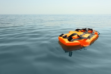 Photo of Orange life jacket floating in sea. Emergency rescue equipment