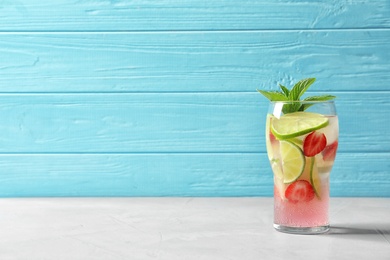 Photo of Natural lemonade with lime and strawberries in glass on table