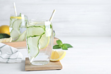 Photo of Refreshing water with cucumber, lemon and mint on white table