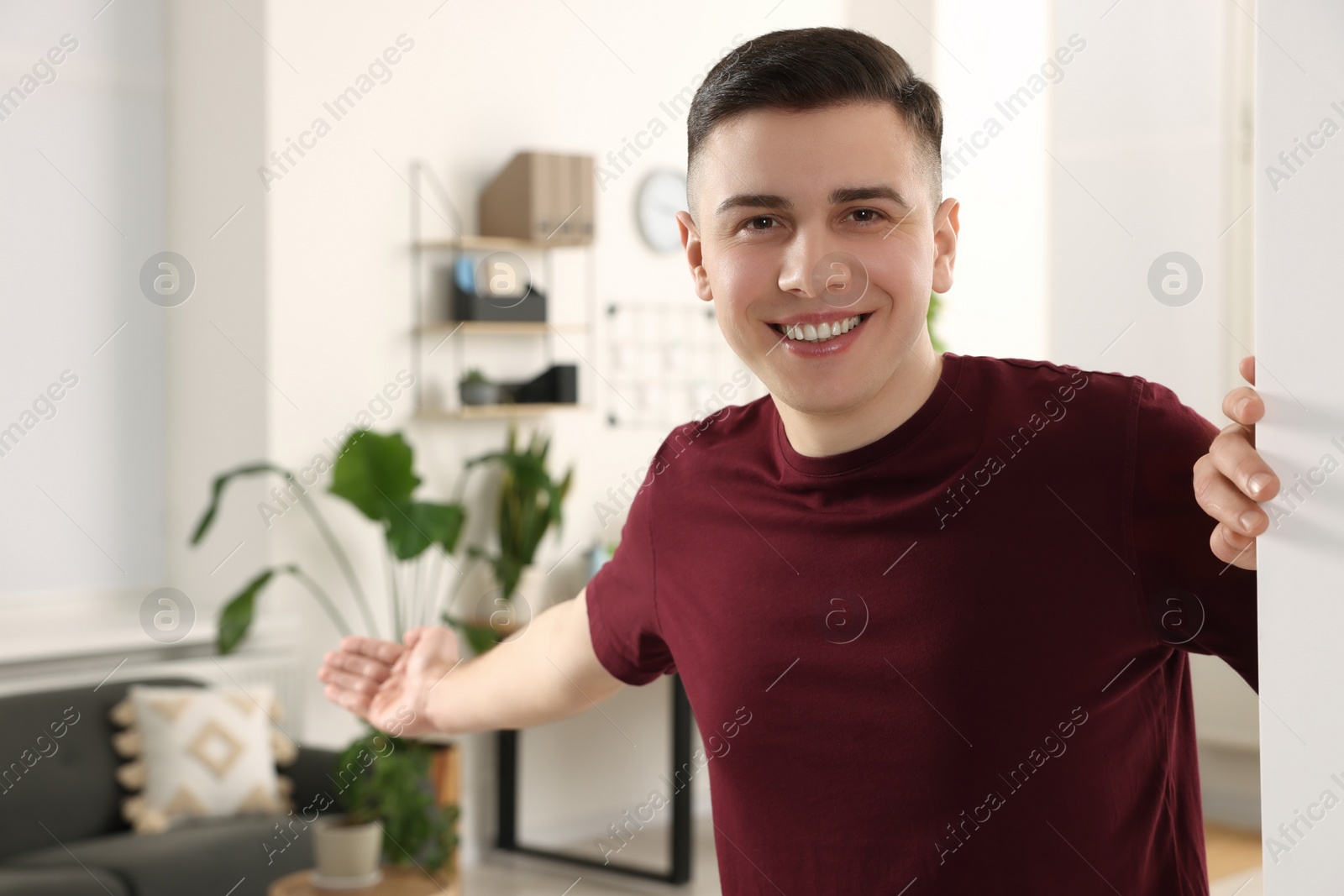 Photo of Handsome man inviting to come in room at home