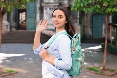 Photo of Travel blogger with backpack recording video on city street