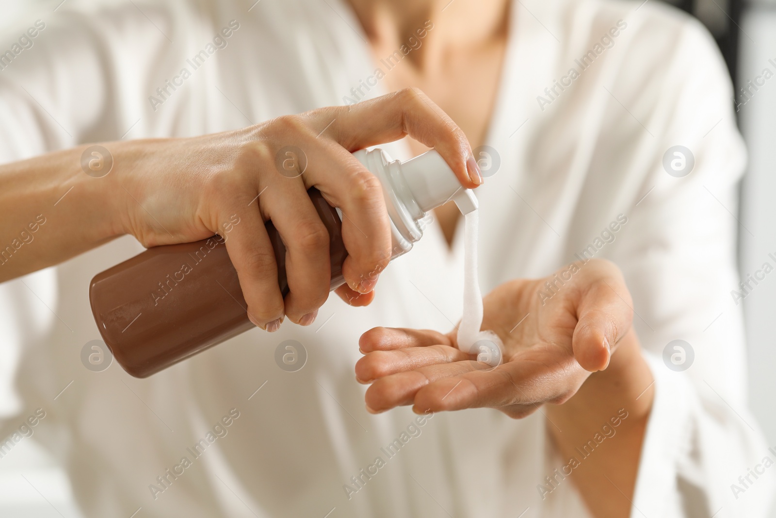 Photo of Woman applying self-tanning product onto hand, closeup