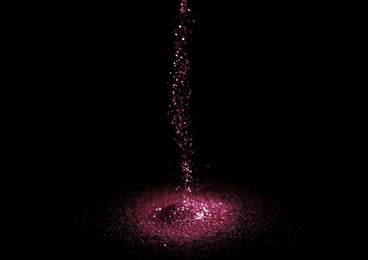Photo of Sprinkling rose glitter on black background, bokeh effect