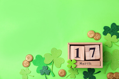 Flat lay composition with wooden block calendar on light green background, space for text. St. Patrick's Day celebration