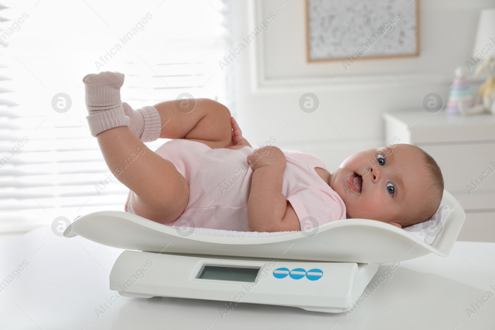 Photo of Cute little baby lying on scales at home