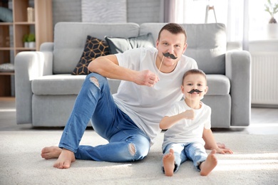 Photo of Happy dad and his son having fun at home. Father's day celebration