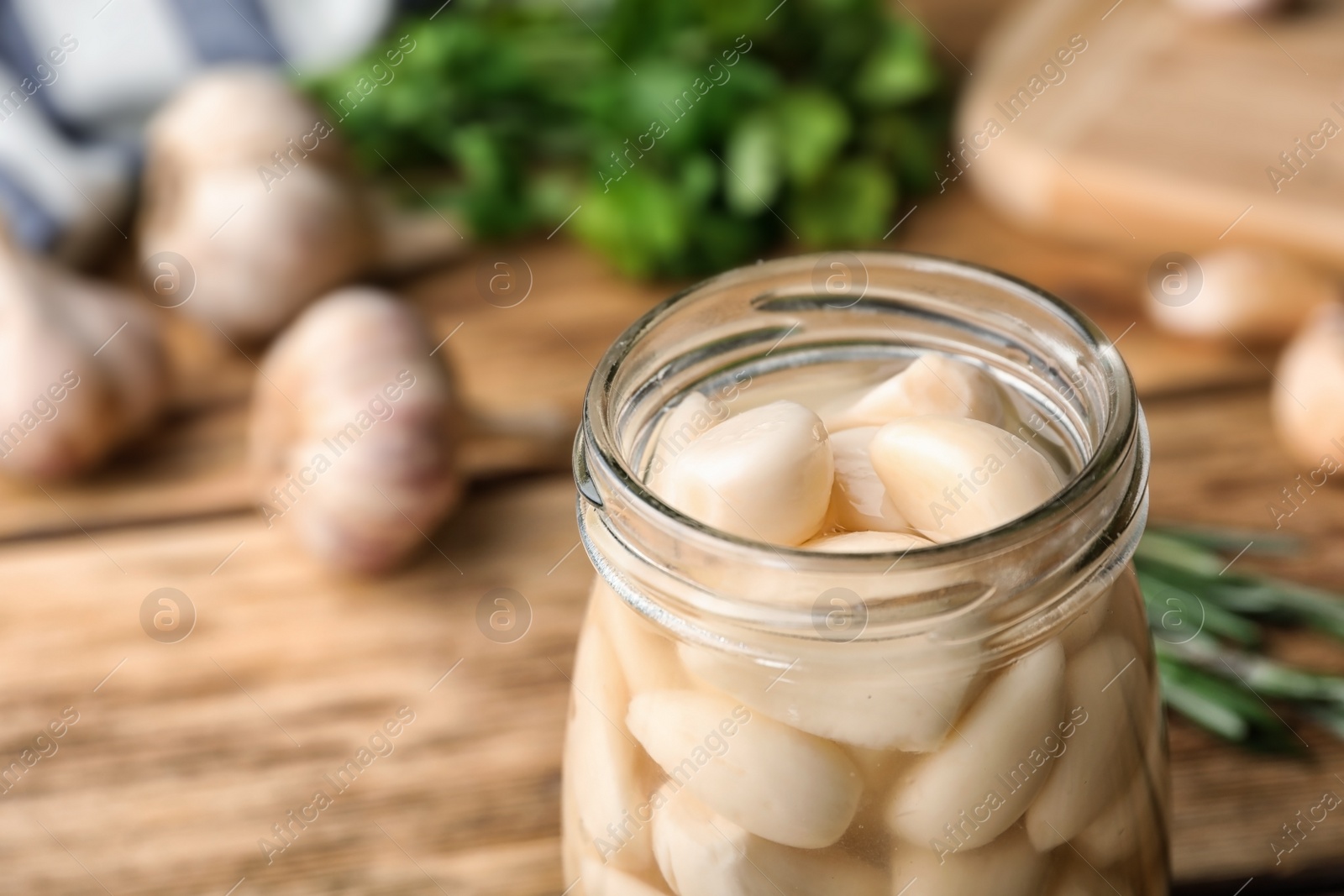 Photo of Preserved garlic in glass jar on table, closeup. Space for text