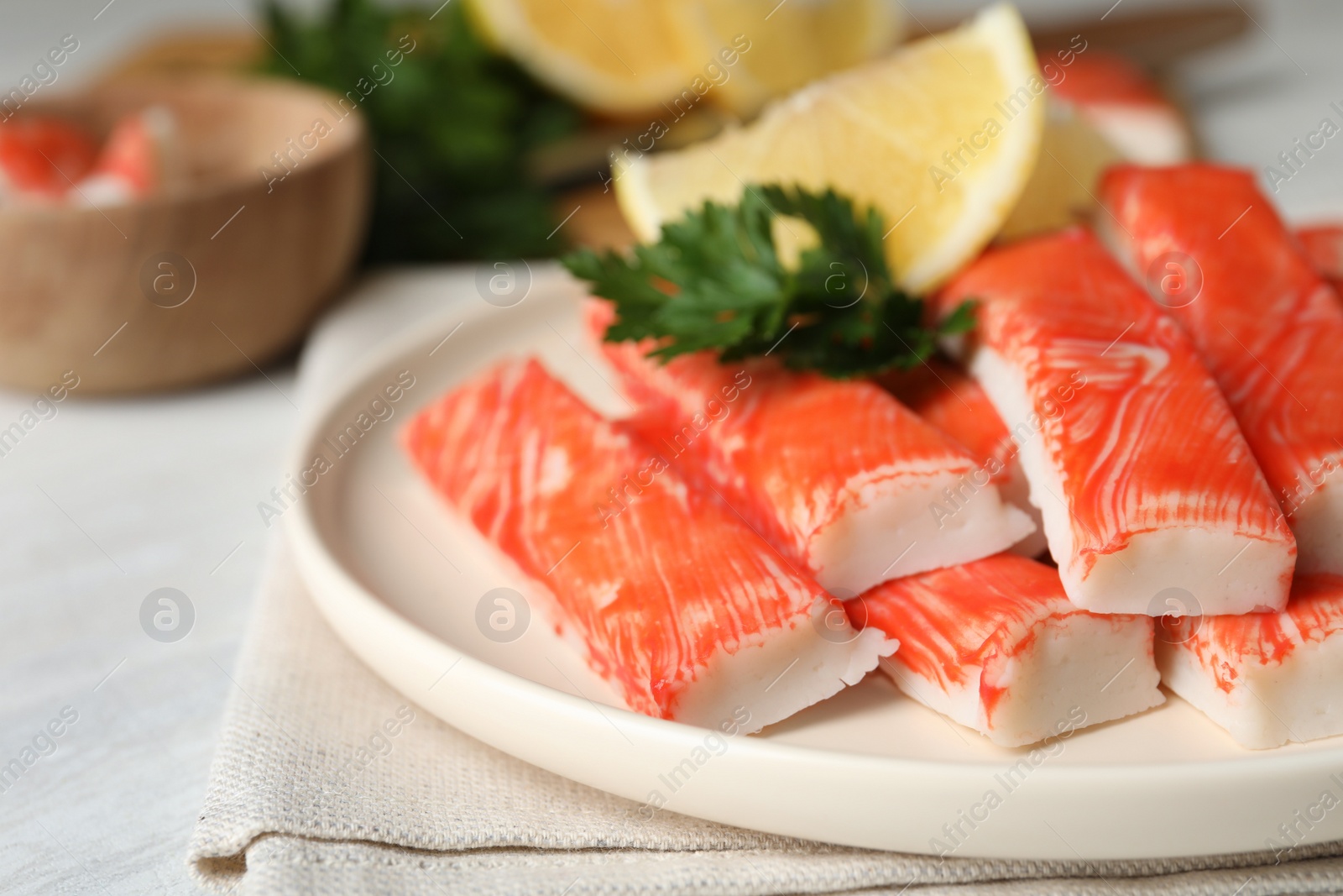 Photo of Plate of fresh crab sticks with lemon on white table, closeup