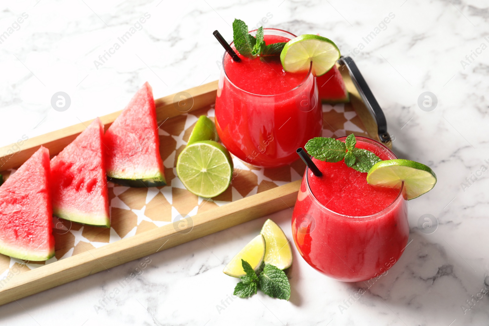 Photo of Summer watermelon drink in glasses and sliced fruits on table