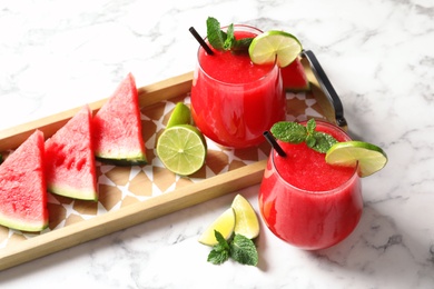 Summer watermelon drink in glasses and sliced fruits on table