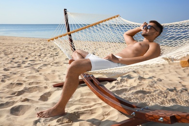 Photo of Young man relaxing in hammock on beach