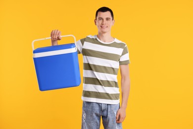 Man with blue cool box on orange background