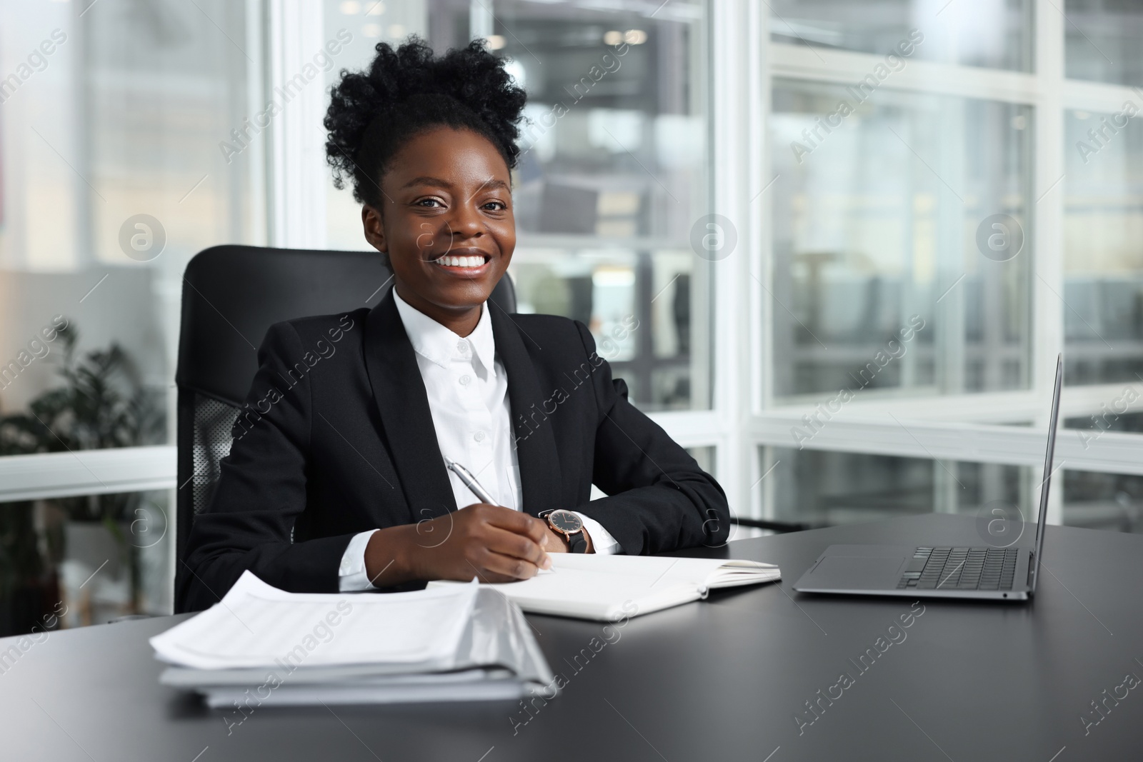 Photo of Happy woman working at table in office. Lawyer, businesswoman, accountant or manager