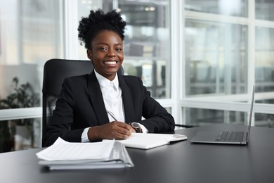 Photo of Happy woman working at table in office. Lawyer, businesswoman, accountant or manager