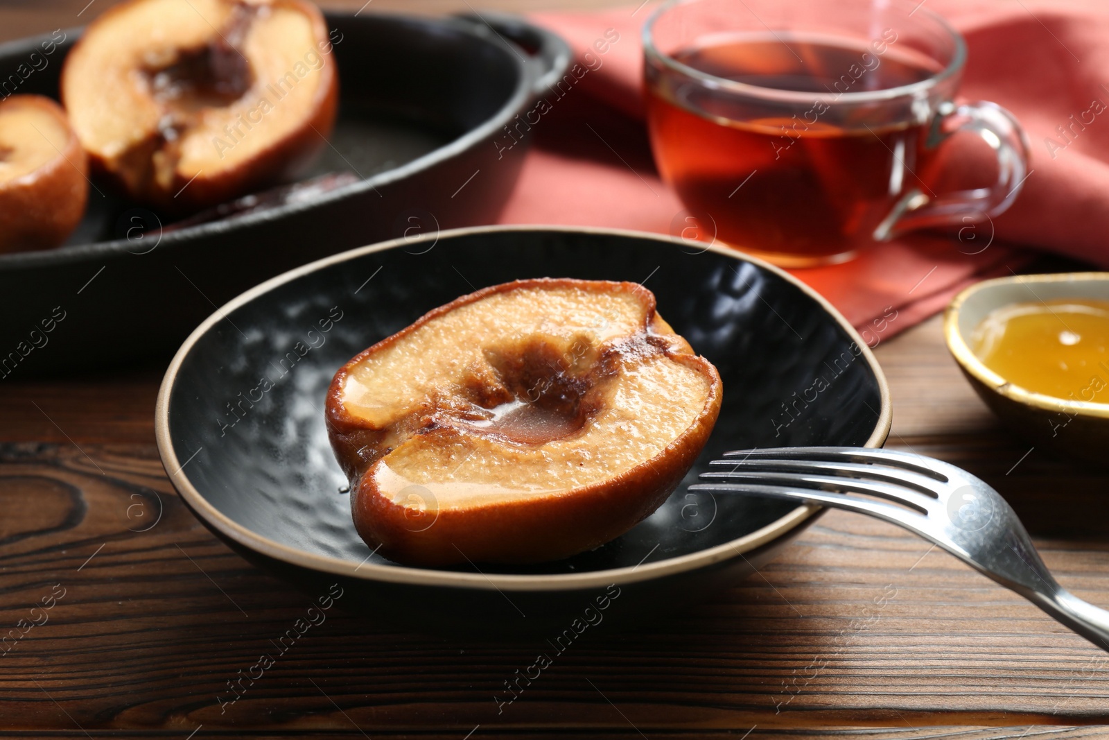 Photo of Tasty baked quince with honey in bowl on wooden table, closeup
