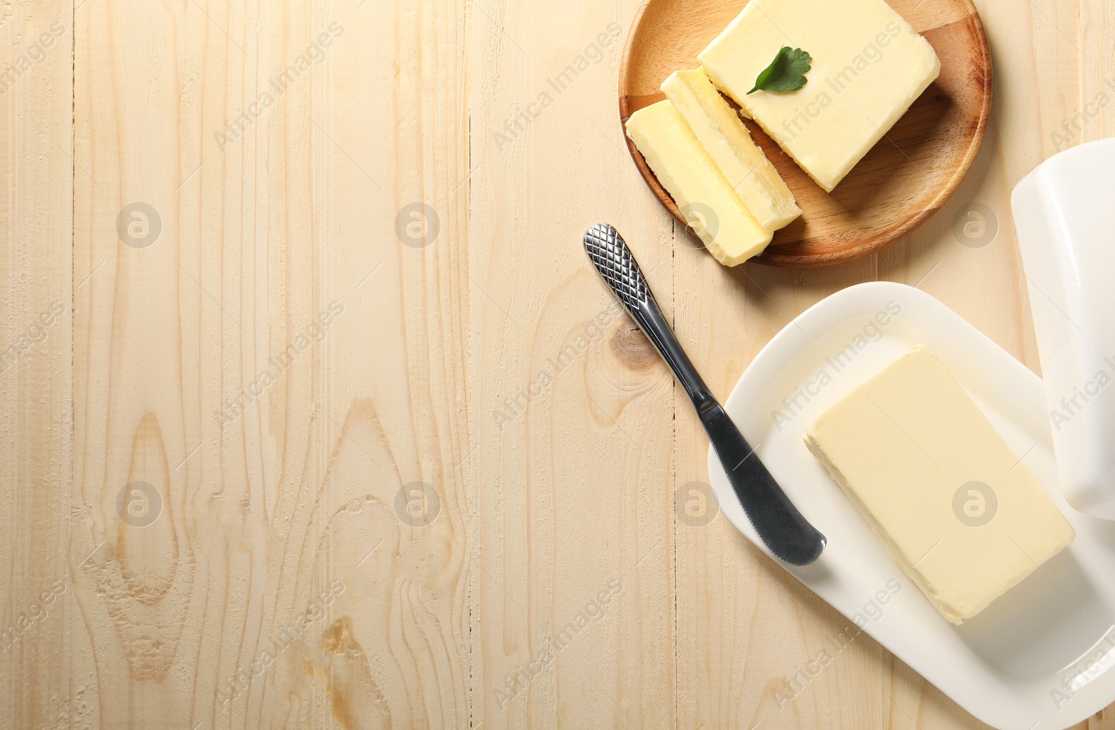 Photo of Tasty butter and knife on wooden table, flat lay. Space for text