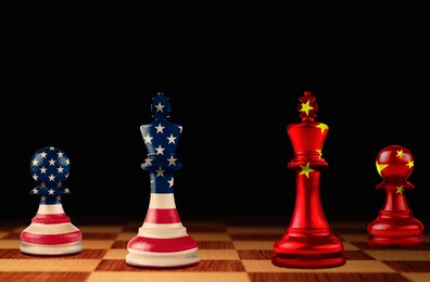 Chess pieces in color of national flags on board against black background. Trade war