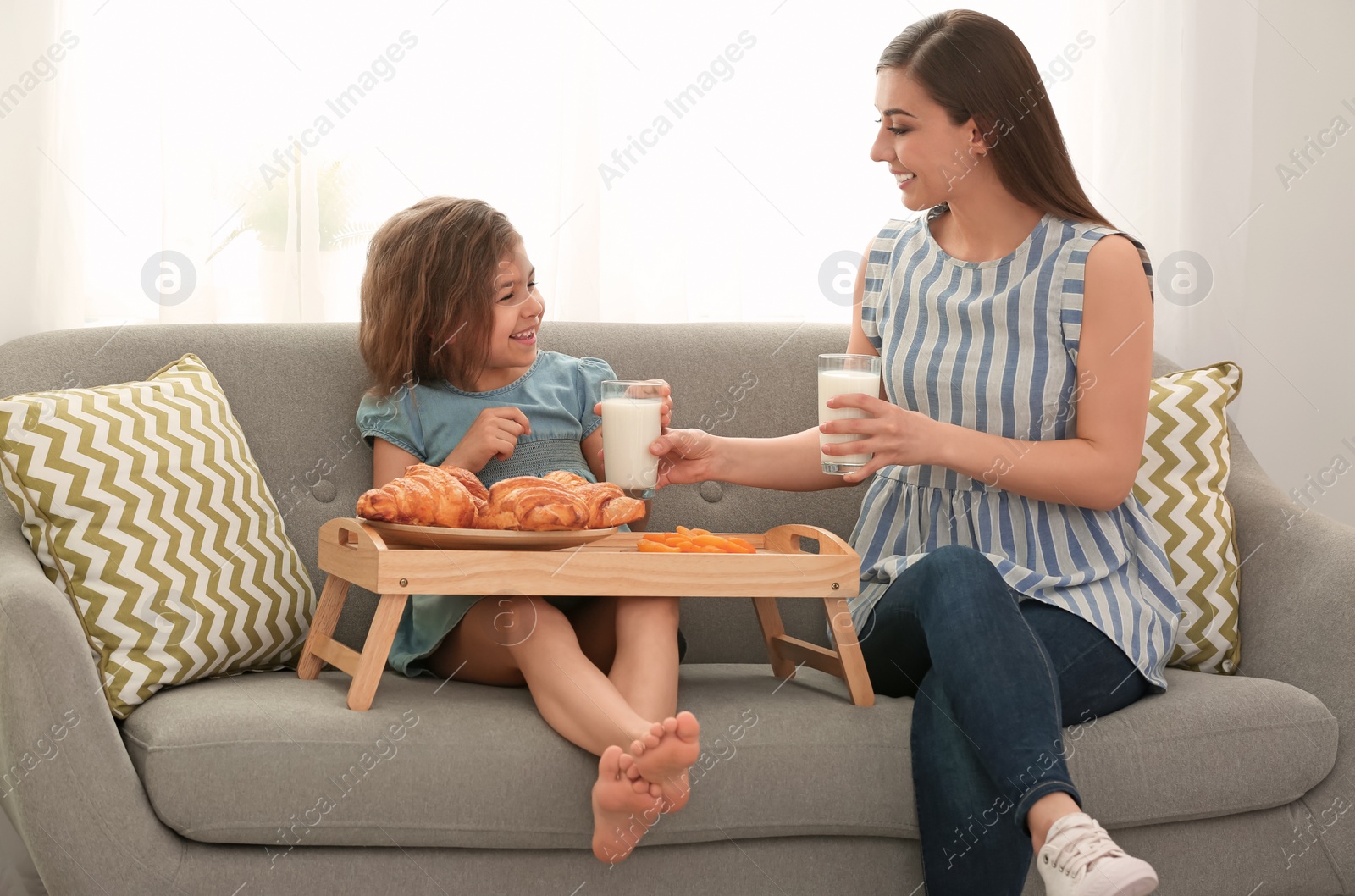 Photo of Mother and daughter having breakfast with milk in living room