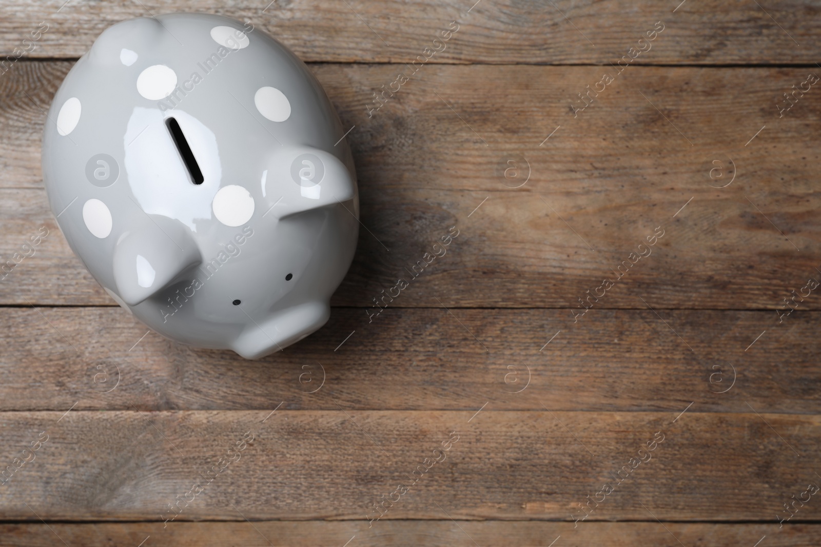 Photo of Top view of piggy bank on wooden table, space for text. Money savings