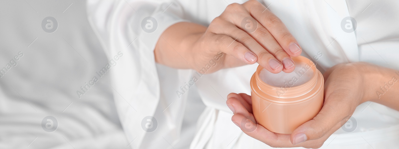 Image of Woman taking hand cream from jar indoors, closeup. Banner design