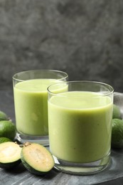 Photo of Fresh feijoa smoothie and fresh fruits on grey board, closeup