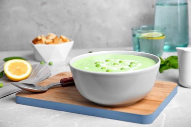 Photo of Green pea soup in bowl on wooden board