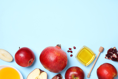 Photo of Honey, apples and pomegranates on light blue background, flat lay with space for text. Rosh Hashanah holiday