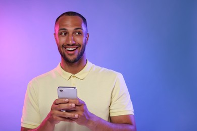 Photo of Happy man sending message via smartphone on color background, space for text