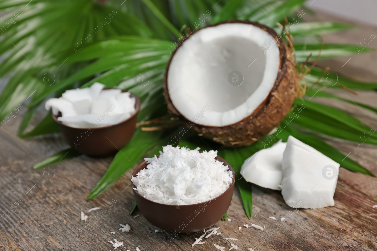 Photo of Bowl with fresh coconut flakes on wooden background