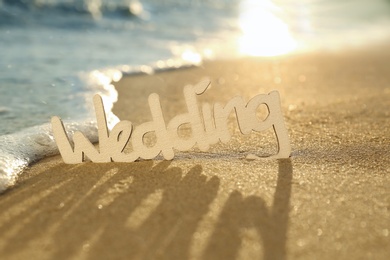 Photo of Word Wedding on sandy beach at sunset