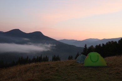 Photo of Picturesque view of mountain landscape with fog and camping tents in early morning