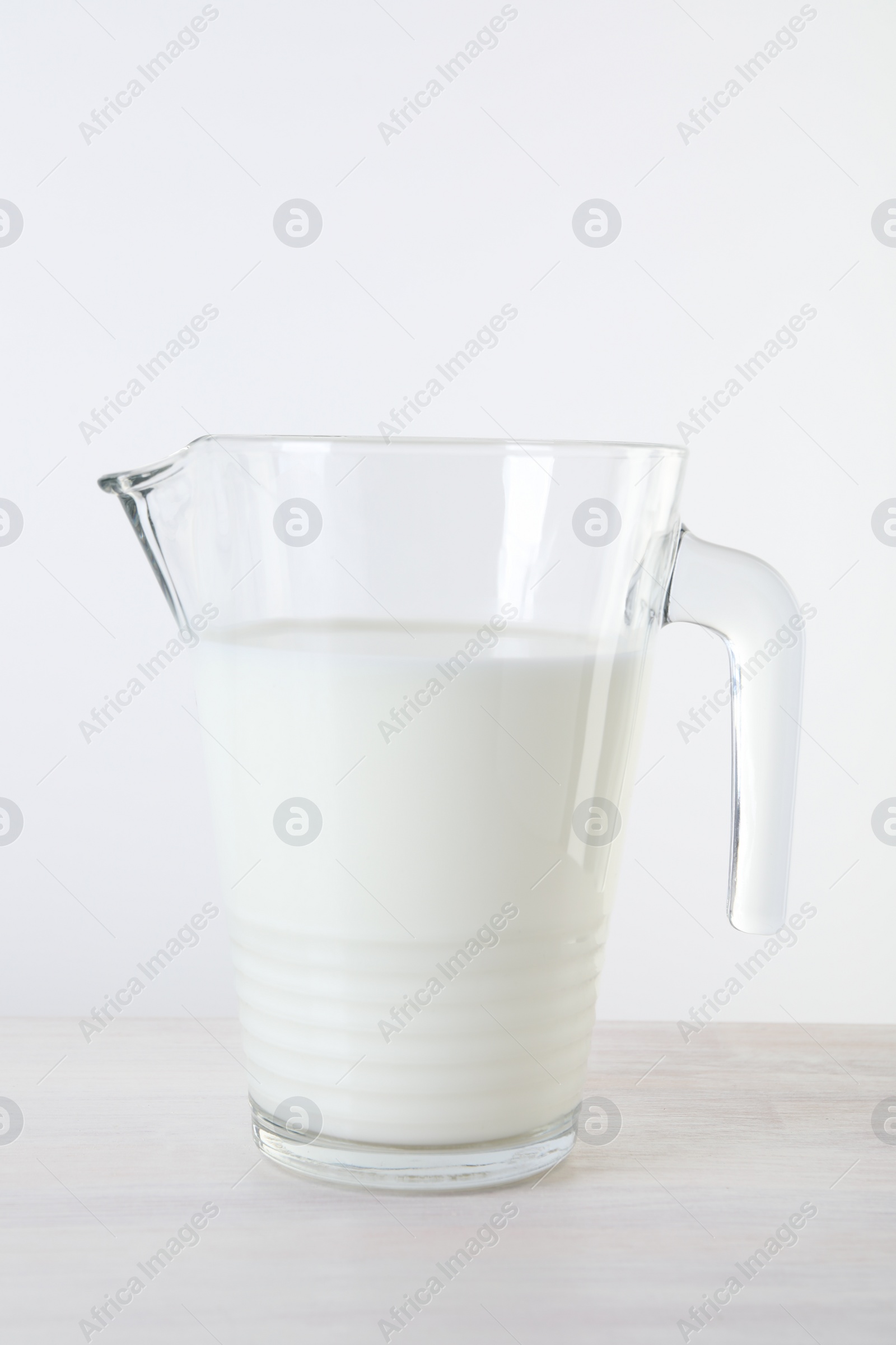 Photo of Jug of fresh milk on wooden table