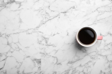 Ceramic cup with hot aromatic coffee on marble background, top view