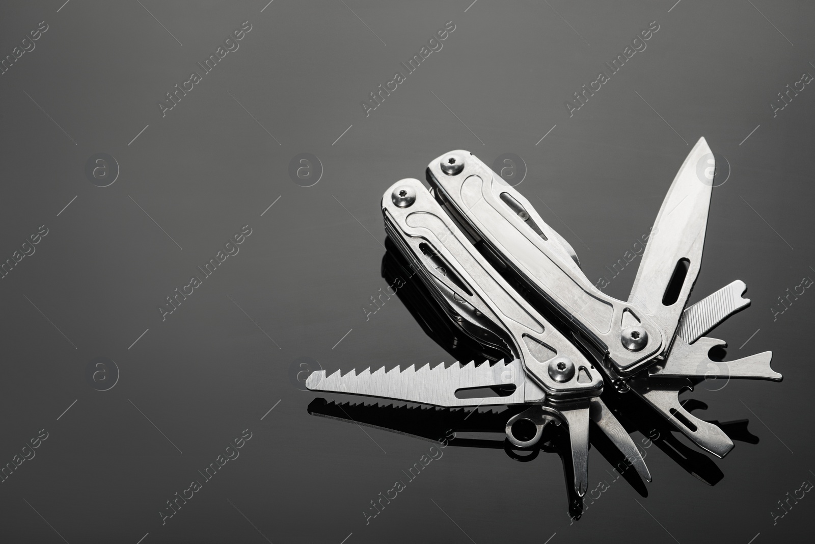 Photo of Compact portable metallic multitool on table, space for text