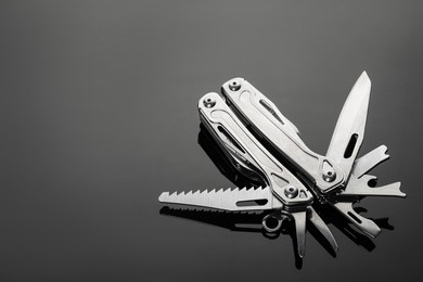 Photo of Compact portable metallic multitool on table, space for text