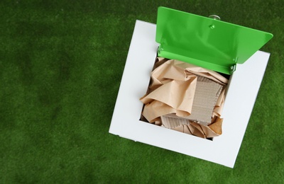 Photo of Trash bin with paper and cardboard on color background, space for text. Recycling concept